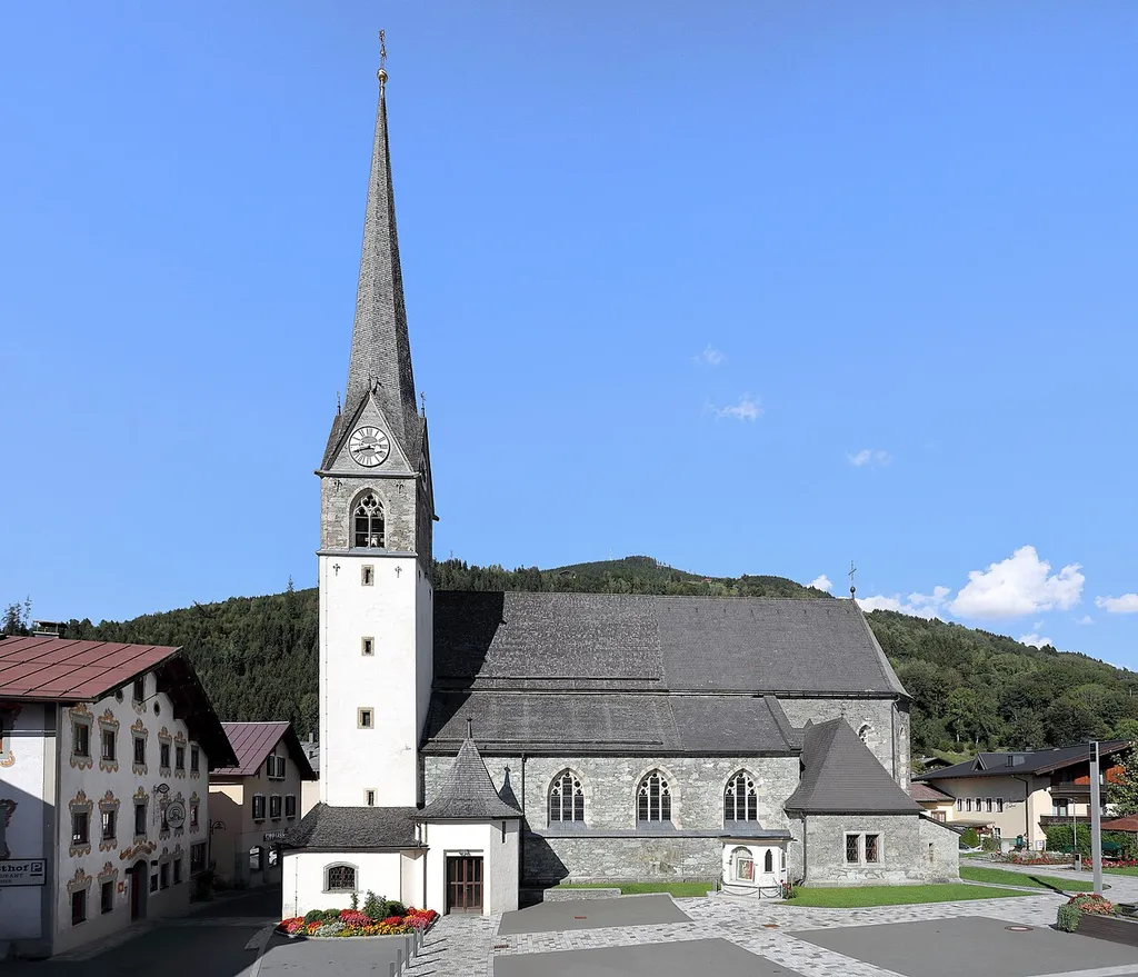 Südsüdwestansicht der röm.-kath. Pfarrkirche Mariä Himmelfahrt in der österreichischen Gemeinde Bruck an der Großglocknerstraße im Salzburger Land. Die Kirche wurde anstelle der 1867 abgebrannten Vorgängerkirche von 1868 bis 1869 nach den Plänen von Friedrich Schmidt im neugotischen Stil gebaut.