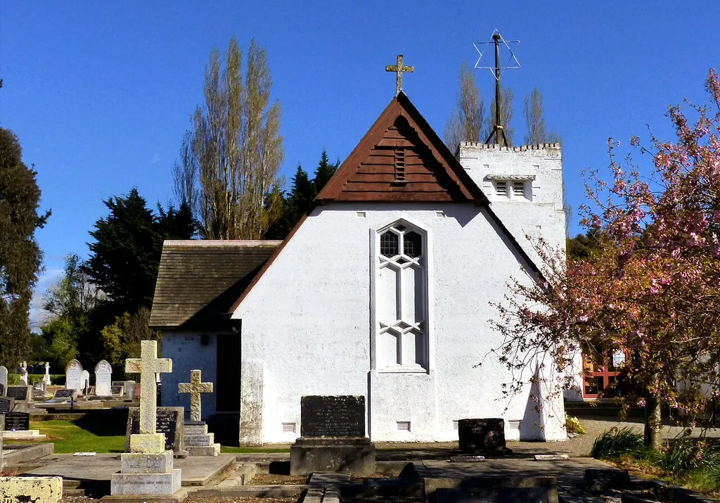 The first St Barnabas Anglican Church was a wooden building which opened on 2 December 1860. It was built on land donated by Rev. John Raven, the first Anglican priest in North Canterbury. The Press of 11 June 1928 reported that the wooden church had been condemned and would be demolished and rebuilt. The small white concrete church was built in 1934 to replace the wooden church. Designed by Cecil Wood, the shingle-roofed church was consecrated on St Barnabas Day 1938. Christchurch carver Frederick Gurney sculpted the stone figure of St Barnabas set in a niche over the main entrance. Inside the church, the font, given in memory of John and Susan Pope, rests on a mill stone from Archers old flour mill at Woodend.