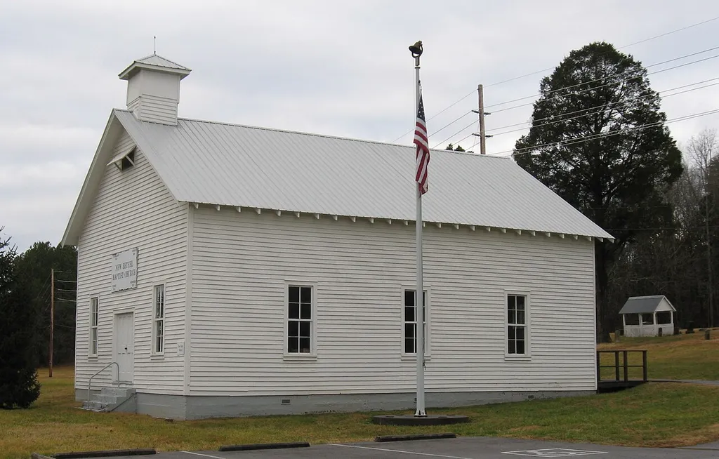 New Bethel Baptist Church (built in 1924) in Bethel Valley in Oak Ridge, Tennessee (in Roane County), with a portion of the church's cemetery in the background. One of the two gravehouses in the cemetery is visible to the right of the church.