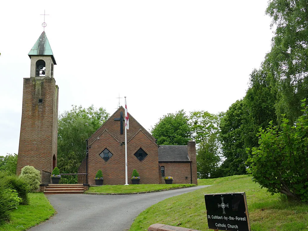 Church of St Cuthbert by the Forest, Mouldsworth. The story behind this Catholic church is that in the 1920’s there was an influx of Irish farm workers, and the landlady of the Station Hotel SJ5170 : The Goshawk, Station Road, Mouldsworth persuaded a curate from St Werburgh’s to come out and say Mass in a pavilion behind the hotel. Mass times therefore had to coincide with train times. After the war, the landlady purchased the land and St Cuthbert's was built from 1953-55 to the designs of Francis Xavier Velarde. The church, with its detached campanile, was listed grade II in 2014 (list entry 1418016). It acquired its present extended name when ‘by the Forest’ was added in 2000.