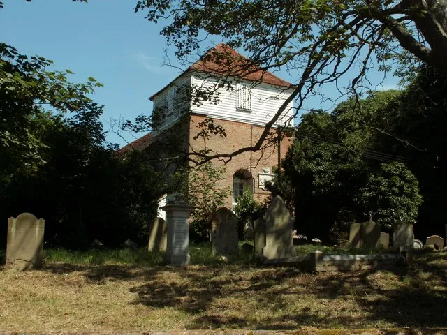 All Saints' church, Great Oakley, Essex. The tower is 18th century, a strange design with weatherboarded upper stage and pyramid roof. The nave is 12th century and the chancel is early 14th century. The church stands alone, just west of the main village.