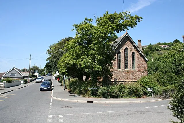 Downderry Church. The Church of St Nicolas Downderry began as a mission church to service the growing population of the village. The building dates from 1905. The bent-over shape of the tree in front of the church is interesting as it may indicate a response by the tree to being battered by strong southwesterly gales in the winter in this exposed coastal location.