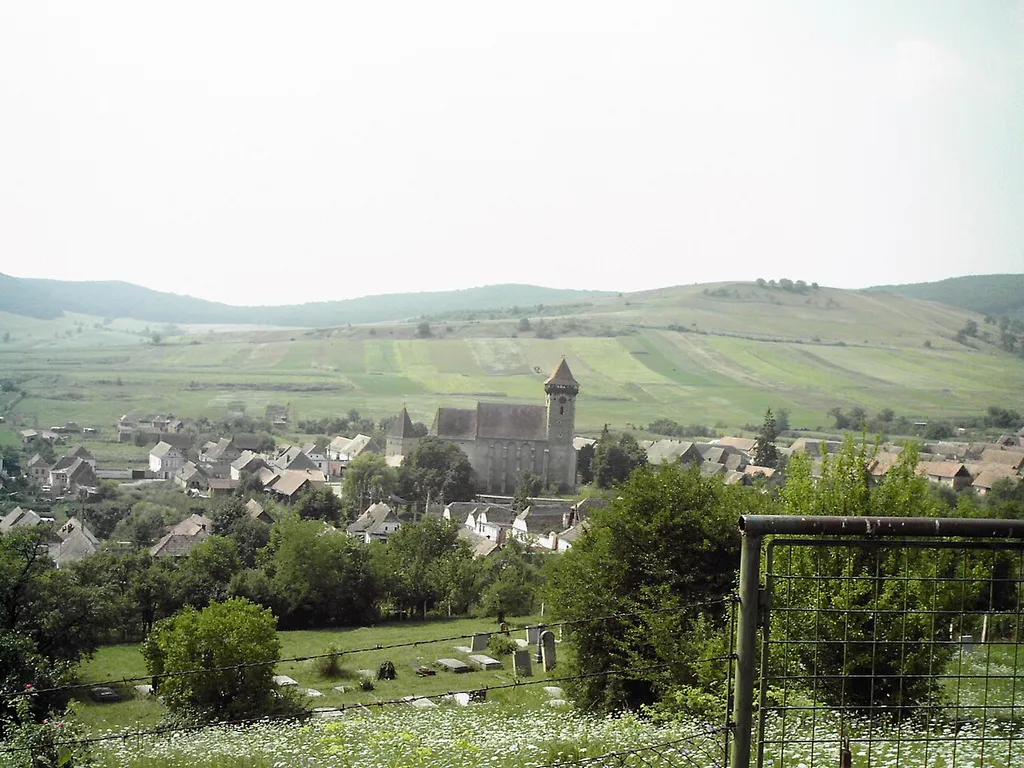 The village of Bagaciu and its fortified church. Massive stone bell-tower with gun emplacements; brick gate tower visible to the left of the church.
