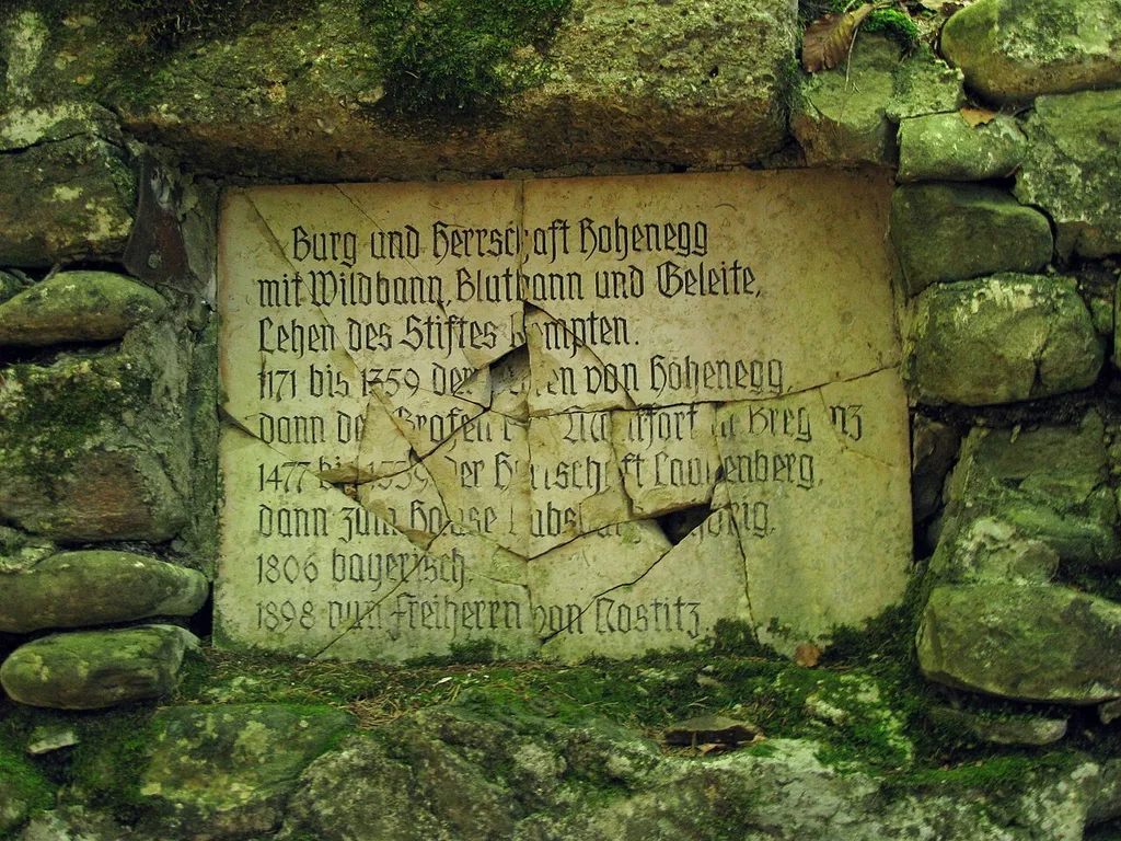 Burgstall Hohenegg, Gedenkstein;Inschrift: Burg und Herrschaft Hohenegg mit Wildbann, Blutbann und Geleite, Lehen des Stiftes Kempten. 1171 bis 1359 der Herren von Hohenegg, dann der Grafen von Montfort in Bregenz, 1477 bis 1539 der Herrschaft Laubenberg, dann zum Hause Habsburg gehörig, 1806 bayerisch, 1898 nun Freiherrn von Nostitz.