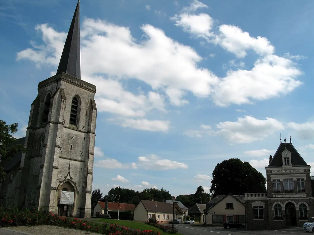 Ailly-le-Haut-Clocher (Somme, France) - Place centrale. L'église, le monument aux morts, et (de l'autre côté de la rue menant à Villers-sous-Ailly) l'hôtel-de-ville. Curieux hasard : Le nuage semble dessiner bizarrement la lettre "a" minuscule, ... comme le "a" de Ailly ?