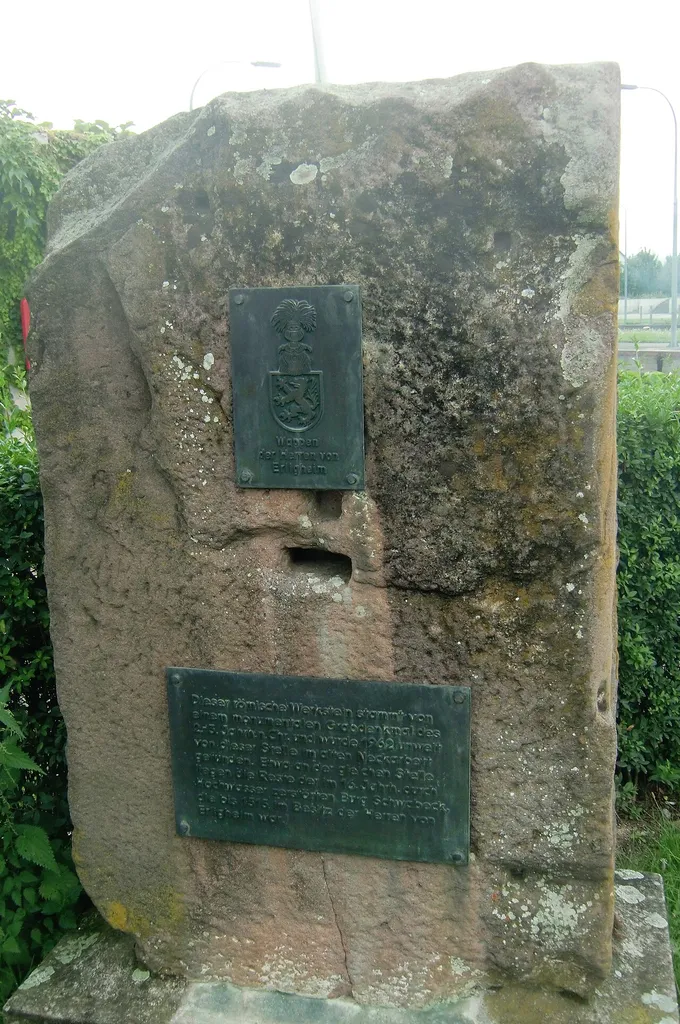 Römischer Werkstein, der jetzt als Gedenkstein an die ehemalige Burg Schwabeck dient. Aufschriften: "Wappen der Herren von Erligheim." "Dieser römische Werkstein stammt von einem monumentalen Grabdenkmal des 2.-3. Jahrh n. Chr. und wurde 1962 unweit von dieser Stelle im alten Neckarbett gefunden. Etwa an der gleichen Stelle liegen die Reste der im 16. Jahrh. durch Hochwasser zerstörten Burg Schwabeck, die bis 1515 im Besitz der Herren von Erligheim war."