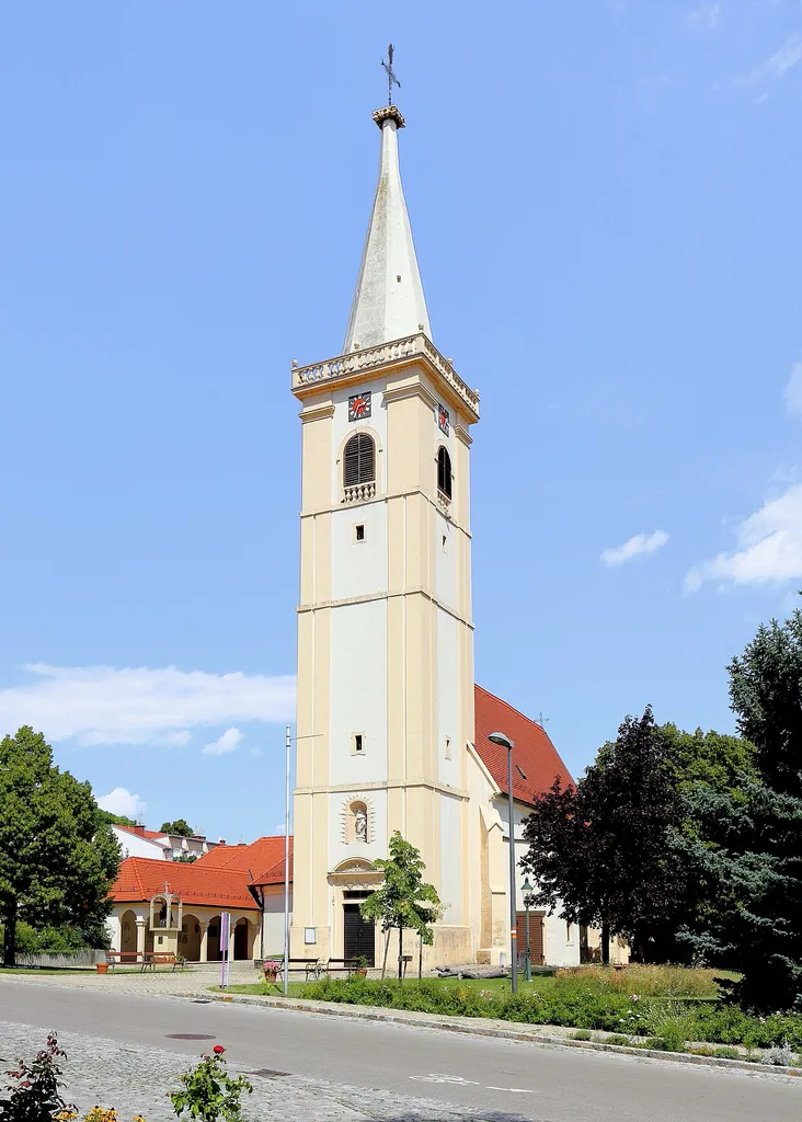 Südwestansicht der spätgotischen röm.-kath. Pfarrkirche hl. Johannes d. Täufer in der burgenländischen Marktgemeinde Großhöflein. Der vorgelagerte, viergeschossige Westturm mit Lisenengliederung wurde 1675 angebaut.