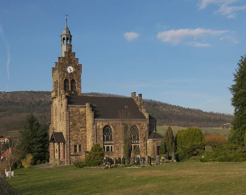 Die Lutherkirche und der zugehörige Friedhof von Kälberfeld, Gemeinde Hörselberg-Hainich in Thüringen. Im Bildhintergrund der Große Hörselberg.