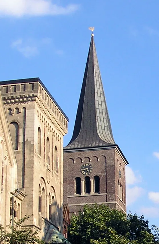 Spitze des Turms der Ruhrorter Jakobuskirche vor dem ehemaligen evangelischen Gemeindehaus