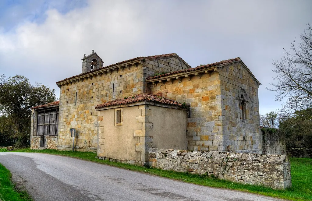 Construida en la primera mitad del siglo XIII, esta iglesia está en la Lloraza, concejo de Villaviciosa, Asturias. La puerta occidental está protegida por el pórtico que se ve a la izquierda de la imagen. Al encontrarlo cerrado y tener espacios muy estrechos entre las maderas no pude fotografiarla.