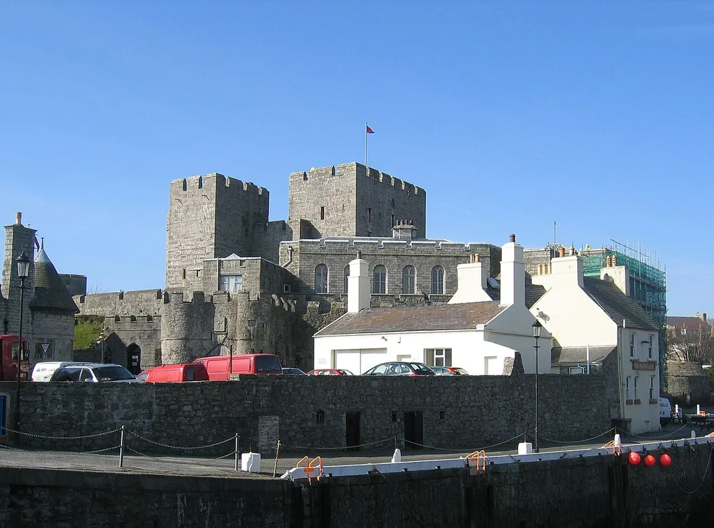 Castle Rushen seen across Castletown Harbour at low tide. The Castle Arms (or Glue Pot) pub is the white building in the foreground of the Castle. Photo cropped to remove clutter.