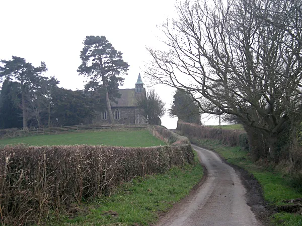 View south down a lane between fields at Smethcott, Shropshire, England, to the church of St Michael and All Angels