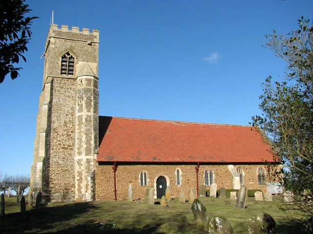 The church of St Michael and All Angels and Holy Cross. The church of St Michael and All Saints and Holy Cross > 1742397 - 1742423 stands isolated, approximately one kilometre to the north-east of the village of Wormegay > 1742337 on the northern edge of Church Wood, beside an unsurfaced farm track that serves as a public bridleway. The site is surrounded by Roman and Saxon remains. The church - built from carstone and once belonging to the Augustinian priory down by the River Nar - was all but rebuilt in the 1890s. The tower dates from the late 14th century but not much dating from medieval times has survived the extensive restoration. The baptismal font > 1742433 is C15 and two image niches retaining medieval paint work > 1742427 can be seen in the east wall.