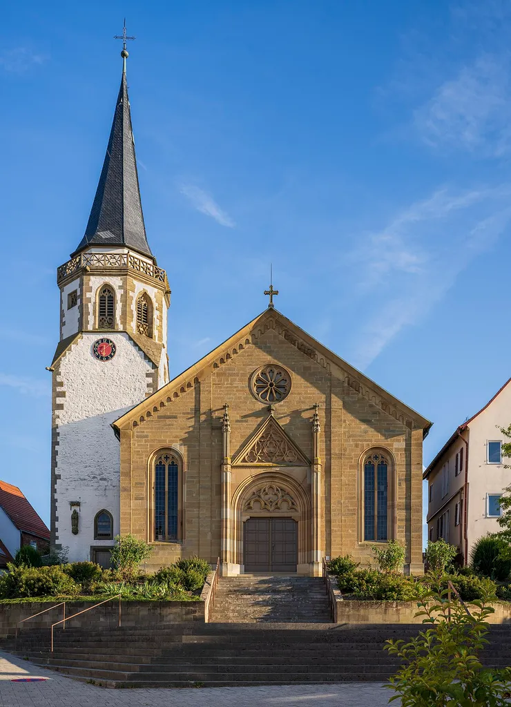 Die evangelische Pfarrkirche St. Gregor in Neckarwestheim, 1844 unter Beibehaltung des älteren Turmes erbaut, Ansicht von Nordwesten.Da die Hauptfassade nach Nord-Nordwesten zeigt, ist eine Aufnahme nur mit Abendsonne möglich, die zwar lange Schatten wirft, dafür aber die plastischen Elemente der Fassade hervorhebt.Hinweis: Der Turmhelm ist tatsächlich leicht zum Schiff geneigt, wie andere Fotos bestätigen – das ist also kein Fehler dieser Aufnahme.